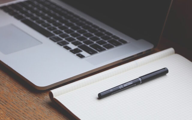 Portátil junto a un bloc de notas sobre una mesa de trabajo